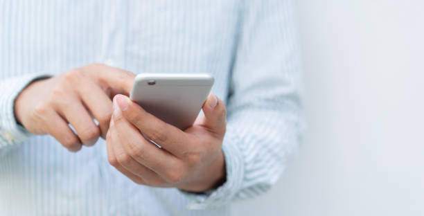 istock Close up asian man using smart phone mobile device for play or shopping online or check time and date for lifestyle concept 1385473791