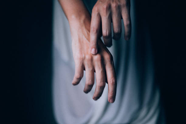 Close-up of a female hands while she is dancing in a white dress, in the dark room