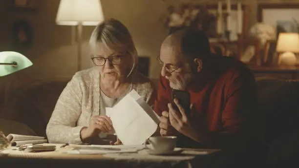 Photo of Aged couple checking utility bills in evening