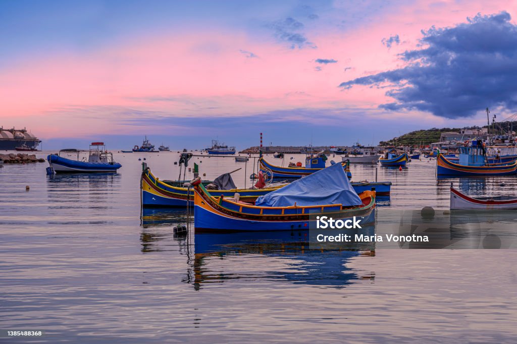 Traditional Maltese boats in Marsaxlokk harbor during sunset, Malta Marsaxlokk Stock Photo