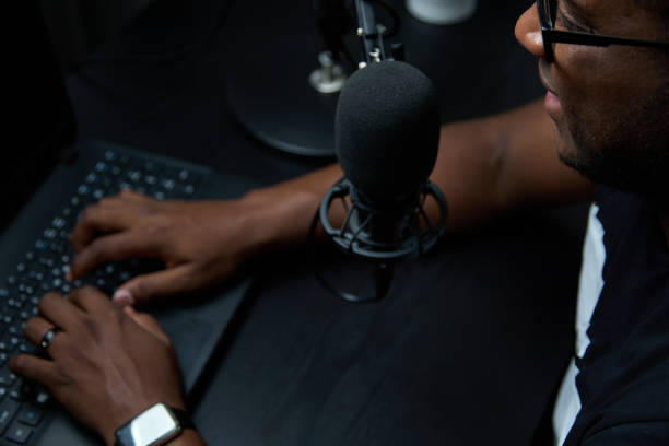hombre con auriculares graba o transmite un podcast usando un micrófono en el estudio - dj de radio fotografías e imágenes de stock