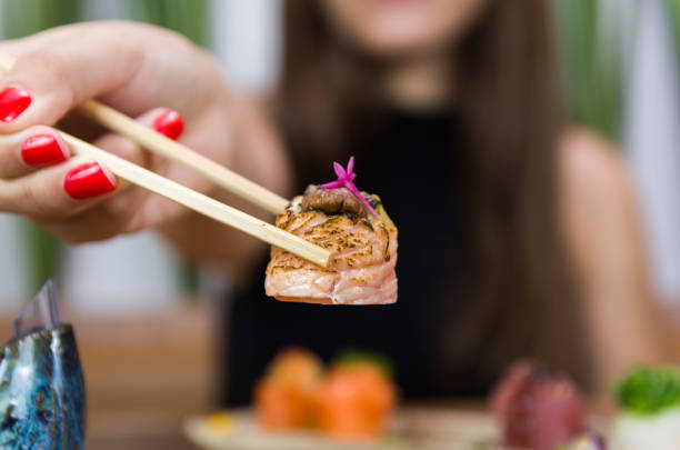 istock Woman eating delicious sushi 1385502075