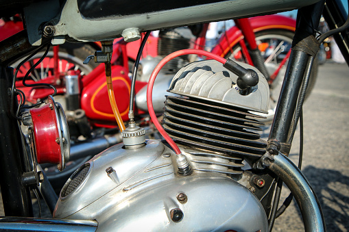 The detail of the polished old motorbike with the two stroke engine. The head has ribbing and is air cooled.