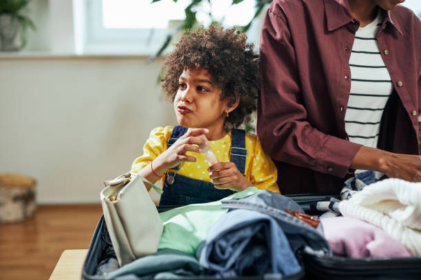 istock Girl is playing while helping her mother to pack suitcase 1385504603