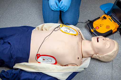 Performing a cardiopulmonary resuscitation (CPR) and using an AED (automated external defibrillator). Waiting for shock. Demonstration on a CPR dummy
