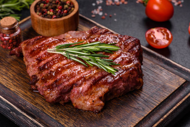 istock Grilled ribeye beef steak, herbs and spices on a dark table 1385507608