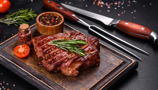 Medium rare sliced grilled striploin beef steak served on wooden board