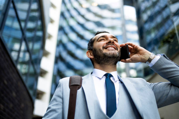 istock Smiling businessman on a way to work using phone 1385508035