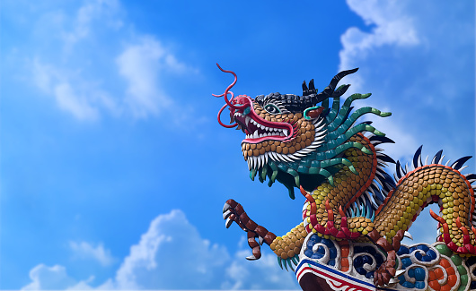 Close-up dragon statue from roof top of Chinese Temple on blue sky background with copy space