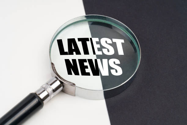 istock On the surface, which is half black and white, lies a magnifying glass inside which is written - LATEST NEWS 1385511789