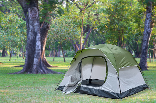 Open medium size tourist tent on blurred campsite in forest location, camping activity and adventure on weekend vacation