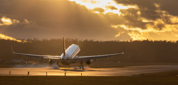 istock Airplane landing againts sunset sky. 1385512764
