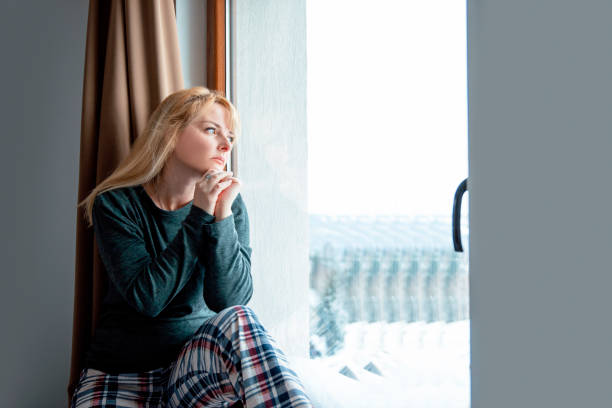 istock Pensive Woman looking out Window 1385513121