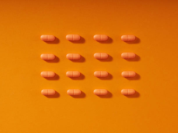istock Pills in a row on orange background. Horizontal composition. 1385514368