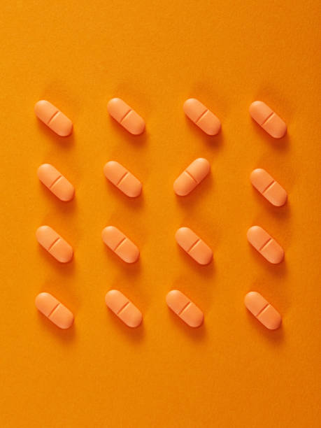 istock Pills in a row on orange background. Vertical composition. 1385514369