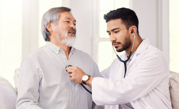 foto de un médico escuchando los latidos del corazón de un hombre mayor durante un chequeo - chest stethoscope medical exam men fotografías e imágenes de stock