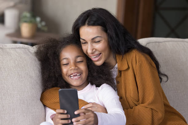 istock Laughing African American mum and daughter using cellphone. 1385517876