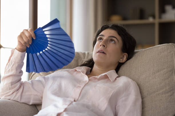istock Exhausted unhappy young Hispanic woman feeling overheated. 1385517933