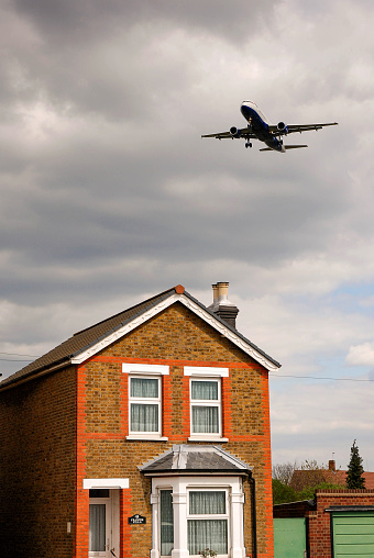 London, England - April 2007: Low flying jet passing overhead a house on the flight path to an airport