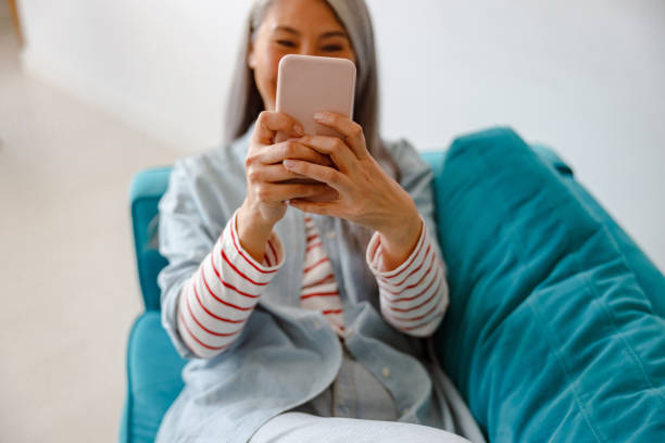 istock Woman lying on couch and using mobile phone at home 1385526401