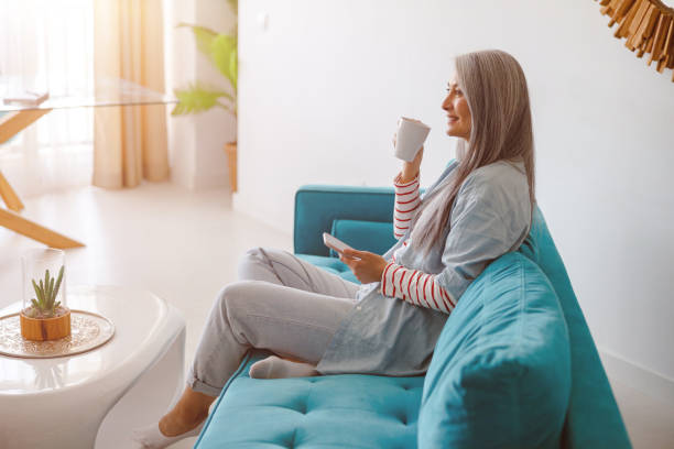 istock Smiling woman drinking coffee and using cellphone at home 1385526407
