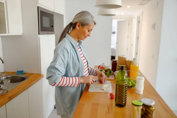 istock Woman cutting tomato for salad in kitchen 1385527856