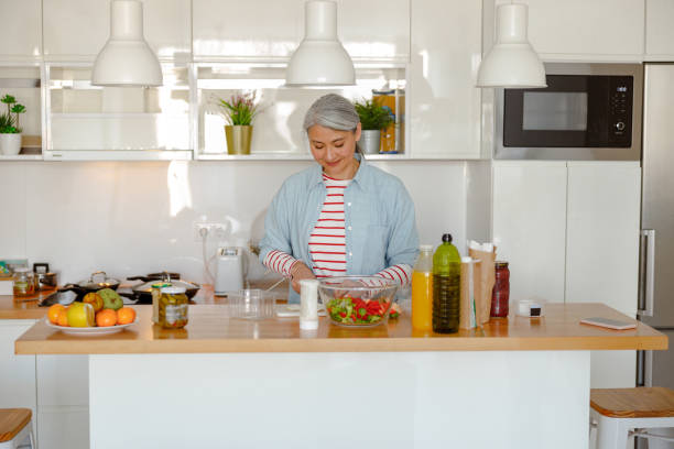 istock Smiling woman making fresh salad in kitchen at home 1385527870