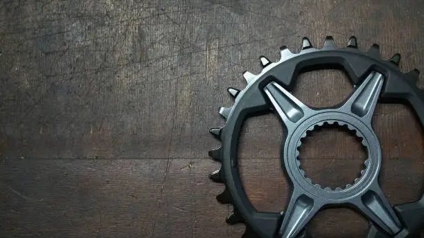 Photo of photo - bike chainwheel - bicycle parts close up on a dark wood background