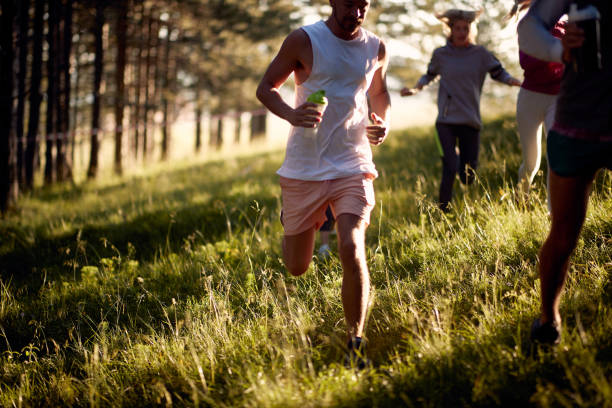 morning run in the woods. pessoas em roupas esportivas correndo na floresta. - couple stretching running jogging - fotografias e filmes do acervo