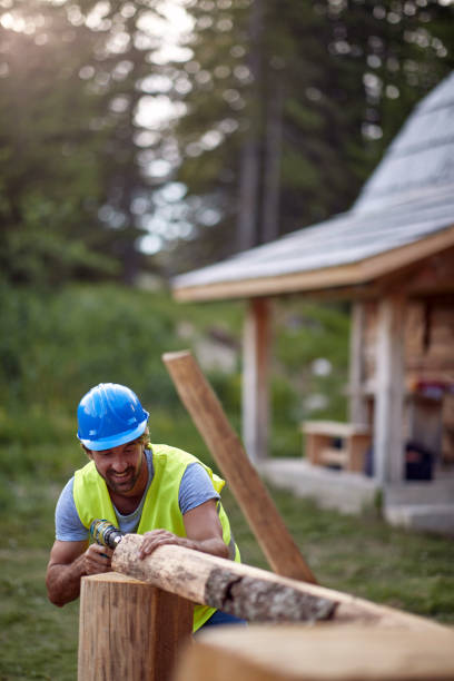 istock worker working with drilling machine on wooden construction. Carpenter building wooden home 1385531209