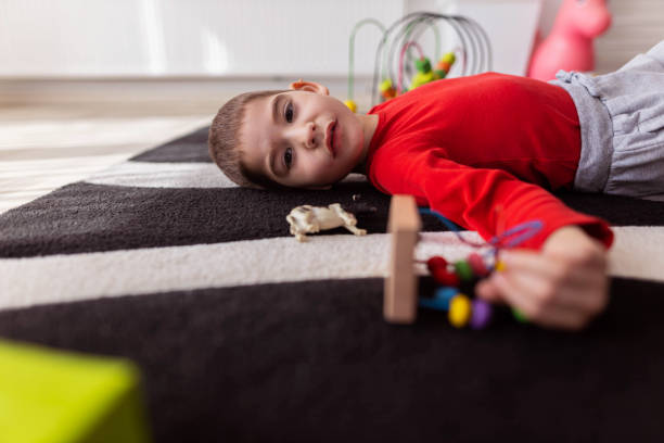 One small boy having a good time playing with his toys on the living room and lying down to take a short nap