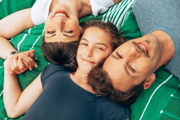 glückliches familienportr�ät im liegen im - women group of people lying down mother stock-fotos und bilder