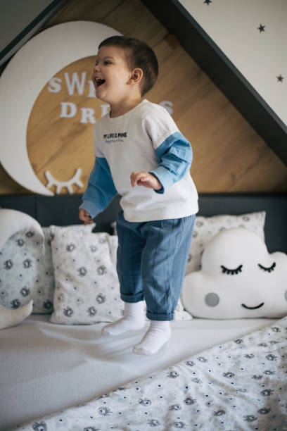 istock Little boy in pajamas jumping on his bed 1385537735