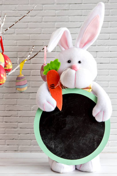istock Easter decoration on white background, bunny holding sign for writing. 1385539226