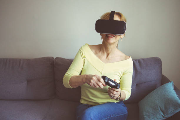 istock A mature woman playing video game using VR and gamepad at home 1385544108