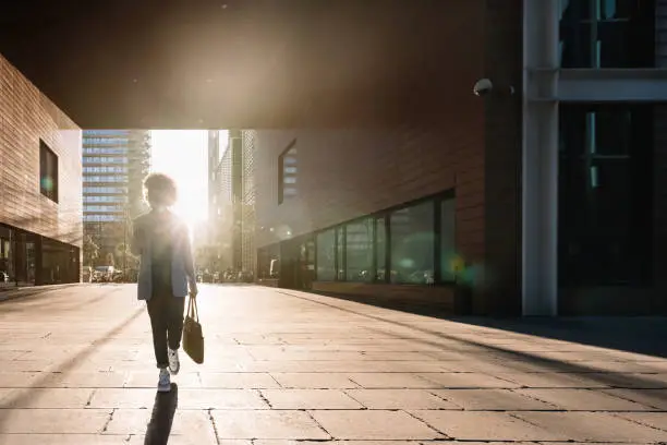 Photo of Silhouette of Black business woman walking in a financial district in the city using phone going to office work. Concept of inspiration, enthusiasm, start-up, feminism