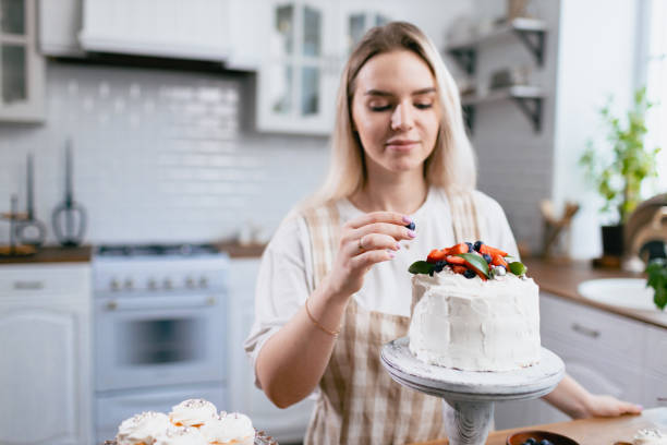 istock Pastry chef confectioner young caucasian woman with cake on kitchen table. 1385568916
