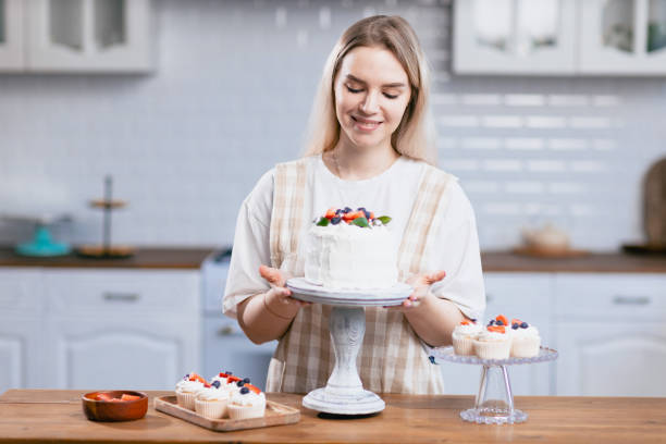 istock Pastry chef confectioner young caucasian woman with cake on kitchen table. 1385568921