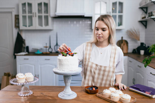 istock Pastry chef confectioner young caucasian woman with cake on kitchen table. 1385568928