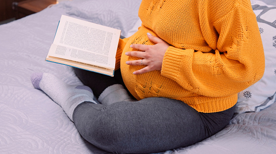 Mujer embarazada leyendo un libro en el dormitorio. photo