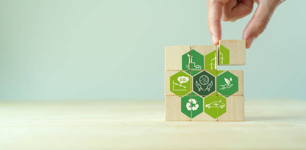 Save of earth, saving environment, net zero emissions concept. Green business and sustainable development. World earth day. Hand puts wooden cubes with clean energy icon standing on eco friendly icon. stock photo