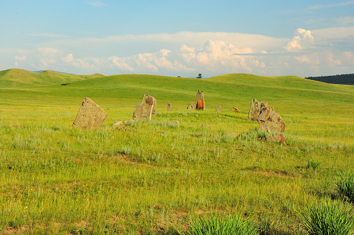 A group of stone slabs of an ancient burial at the foot of the hills in the summer steppe. Safronov barrows, Khakassia, Siberia, Russia.