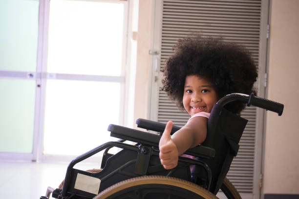 Happy African child sitting on wheelchair. stock photo