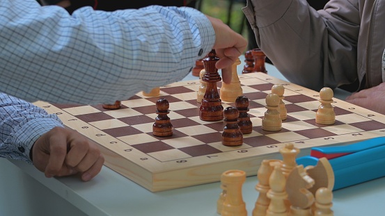 people hands play chess on the street in green sunny summer.