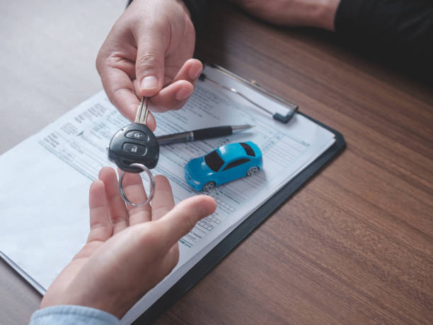 alquiler de coches conceptuales. vista de cerca mano del agente que entrega la llave del automóvil al cliente después de firmar el formulario de contrato de alquiler. - alquiler de coche fotografías e imágenes de stock