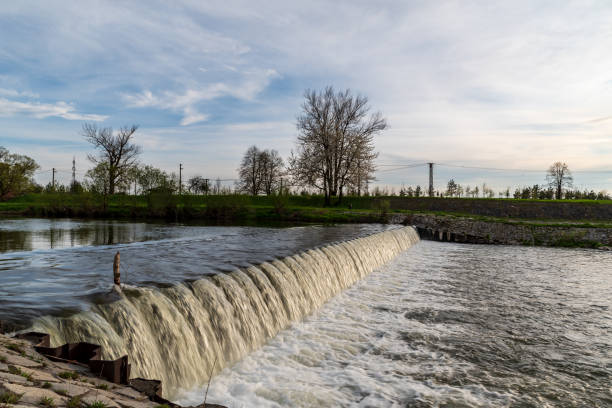 istock River with weir, trees on the background and blue sky with clouds 1385623465