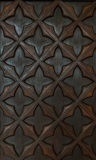 Beautiful surface of an antique wooden door with a carved floral pattern. Medieval decoration of interior and architecture