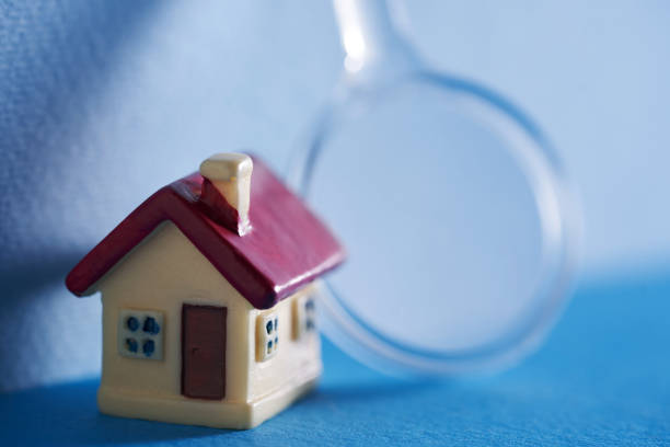istock small model house with magnifying glass against blue backgroun 1385628266