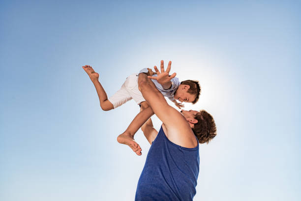 Low angle view of carefree father and son having fun during summer day. Copy space.