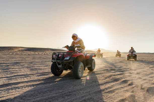 donna felice e i suoi amici che guidano quad nel deserto. - off road vehicle quadbike 4x4 adventure foto e immagini stock